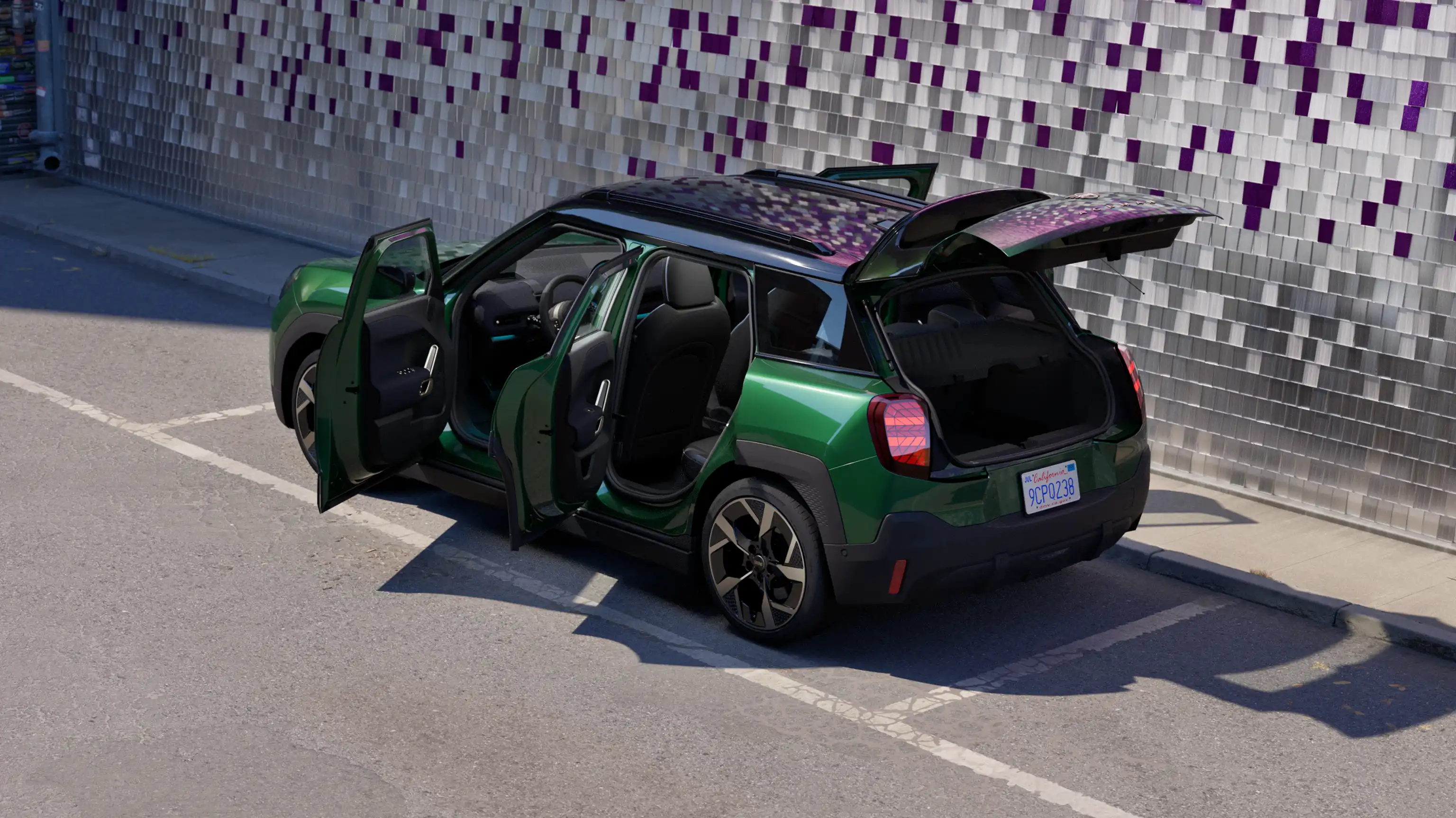Vista traseira lateral de um MINI Aceman elétrico em British Racing Green numa área de estacionamento, com todas as portas abertas e uma parede colorida em segundo plano