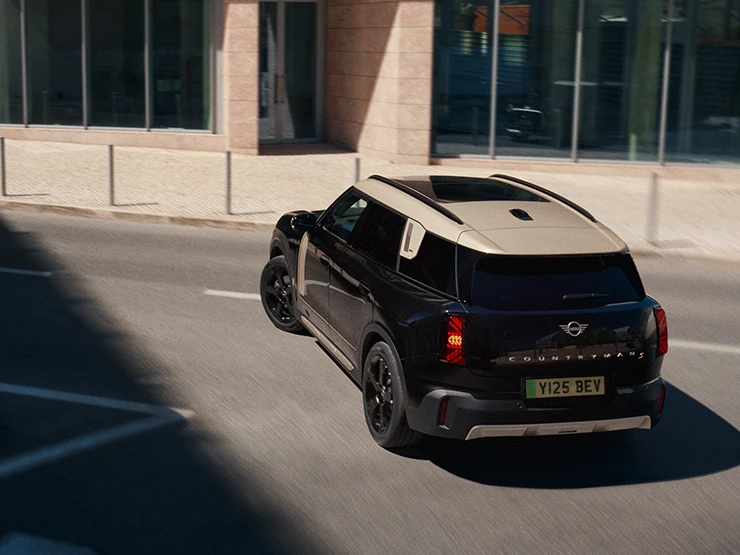 Vista superior traseira do MINI Countryman elétrico em Midnight Black com tejadilho Vibrant Silver estacionado.