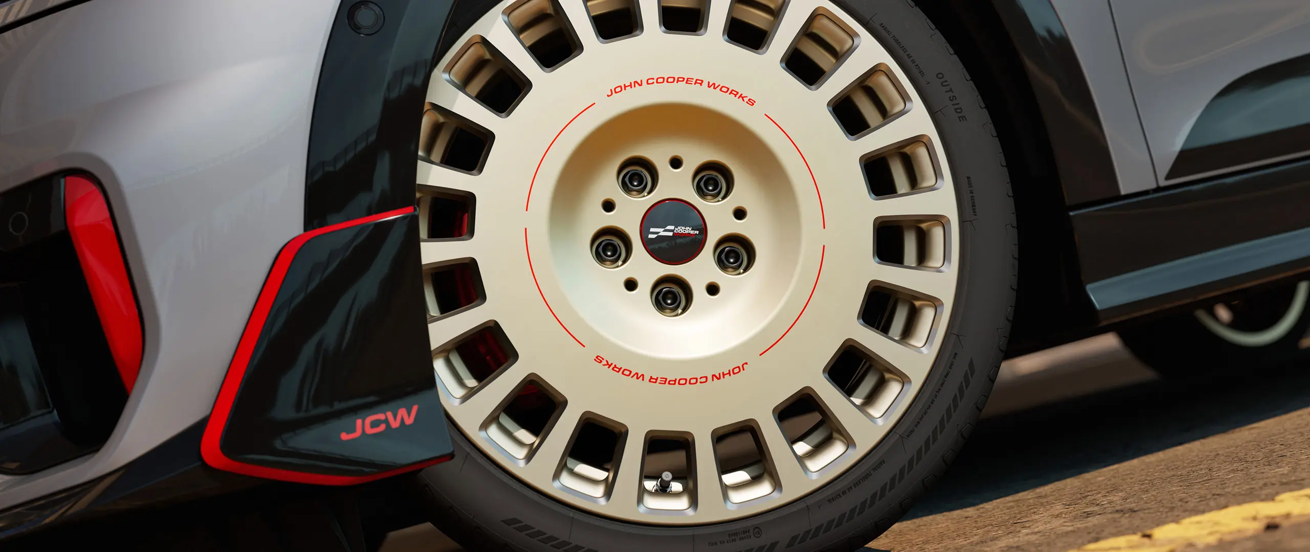 Grande plano dos detalhes de uma roda JCW Rallye Spoke 964 de 18" em Bicolour Vibrant Silver e com winglet dianteiro e fresado brilhante.