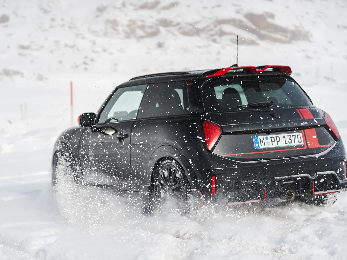 Vista traseira de um MINI Cooper JCW em regime de condução na neve.