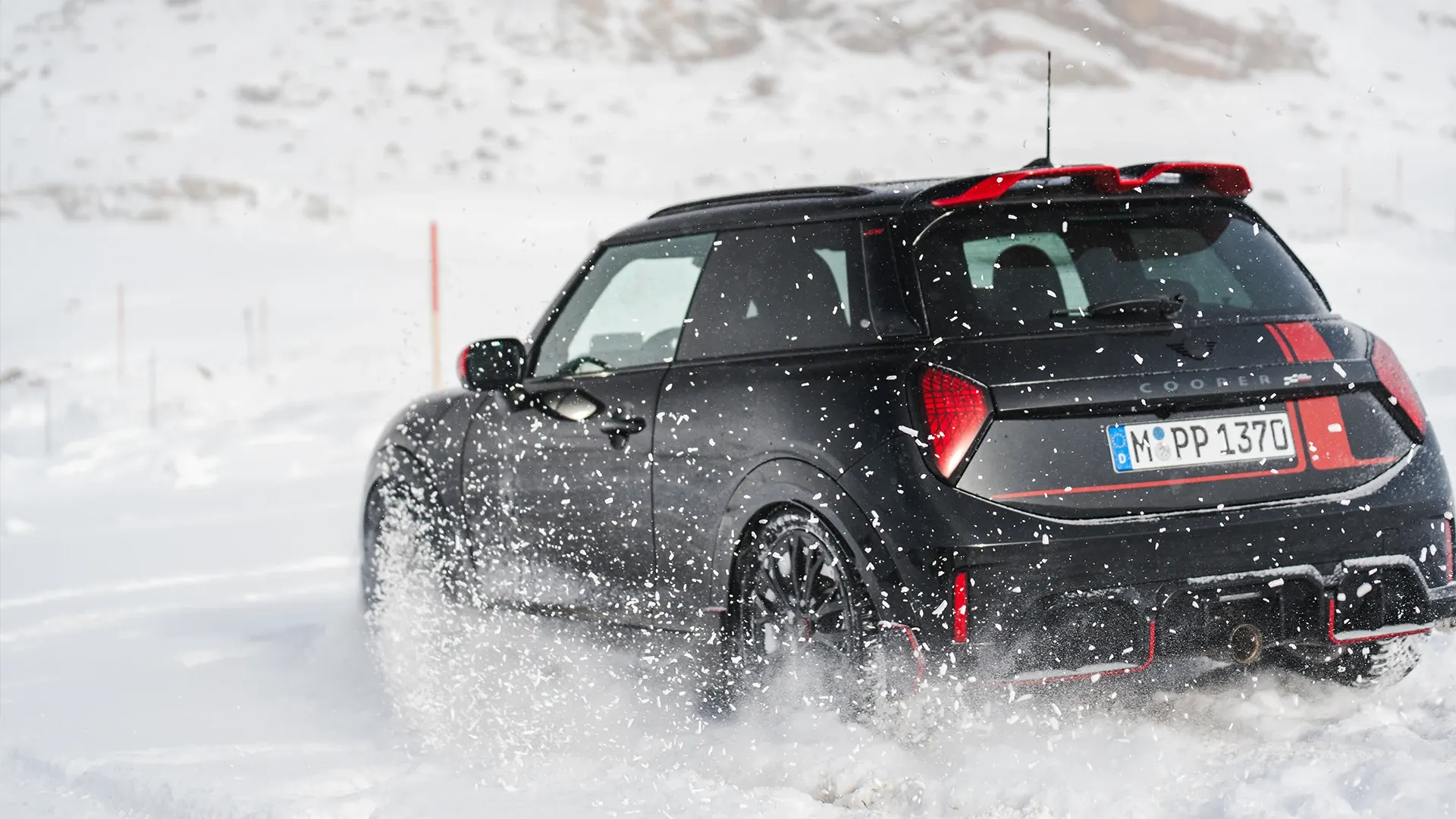 Vista traseira de um MINI Cooper JCW em regime de condução na neve.