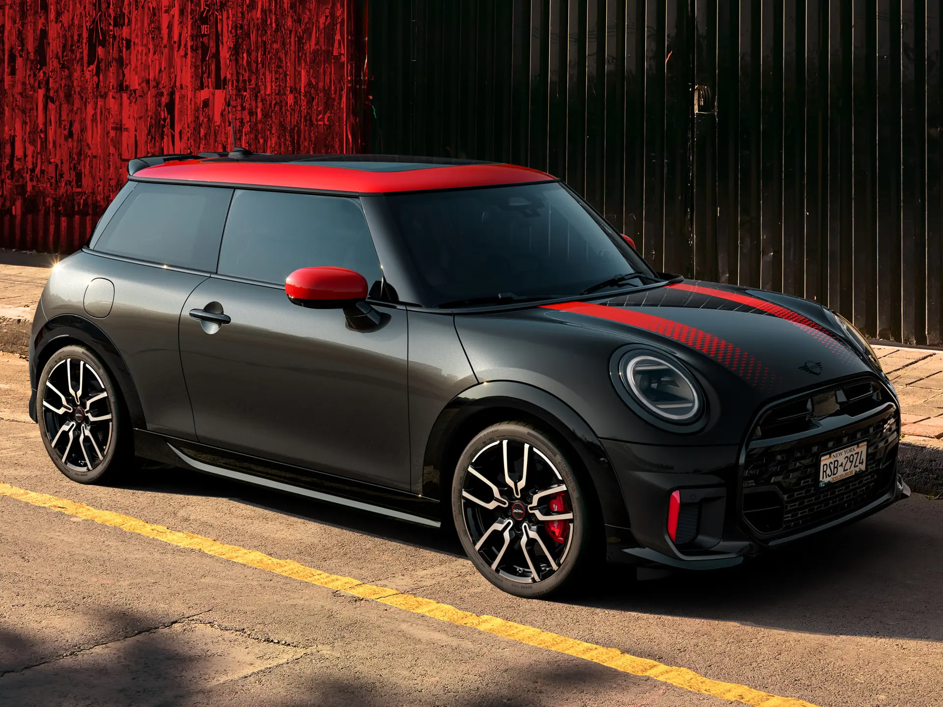 MINI John Cooper Works de 3 portas em Midnight Black com tejadilho e tampas dos espelhos retrovisores em Chili Red e faixas desportivas vermelhas, vista lateral, estacionado na rua.