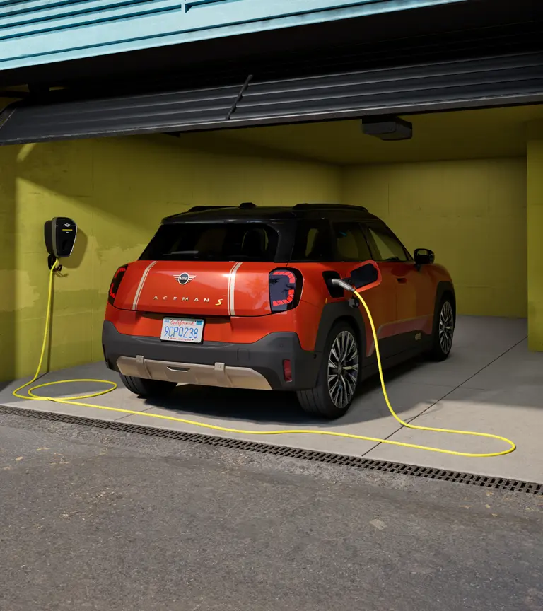 MINI Aceman S Elétrico a ser carregado com a MINI Wallbox Plus, vista traseira, estacionado na garagem.