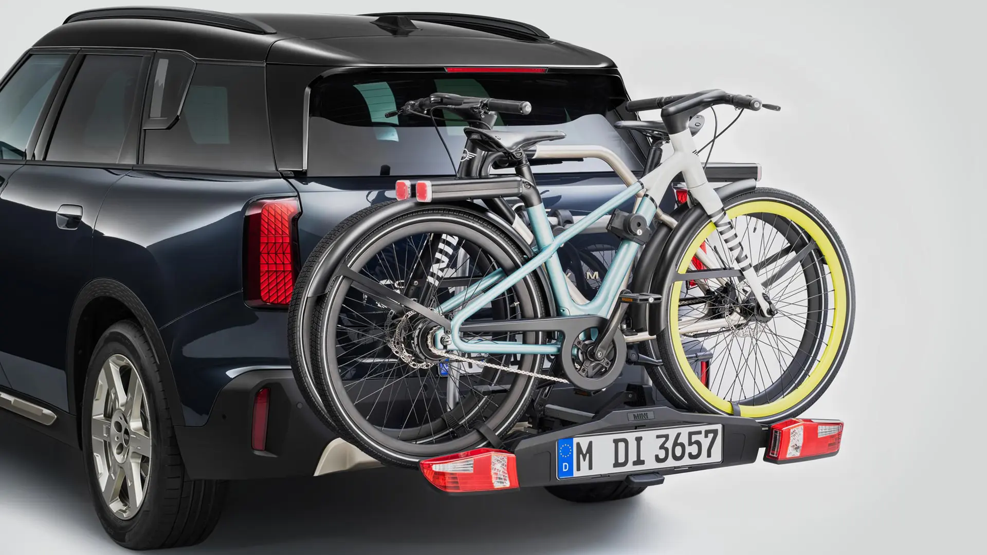 MINI Countryman em preto com um suporte traseiro para bicicletas e duas bicicletas de montanha encaixadas, vista traseira.