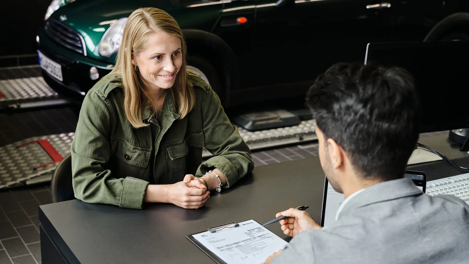 Concessionário MINI com consultor a aconselhar o cliente sobre as opções de serviço, os dois sentados a uma mesa.