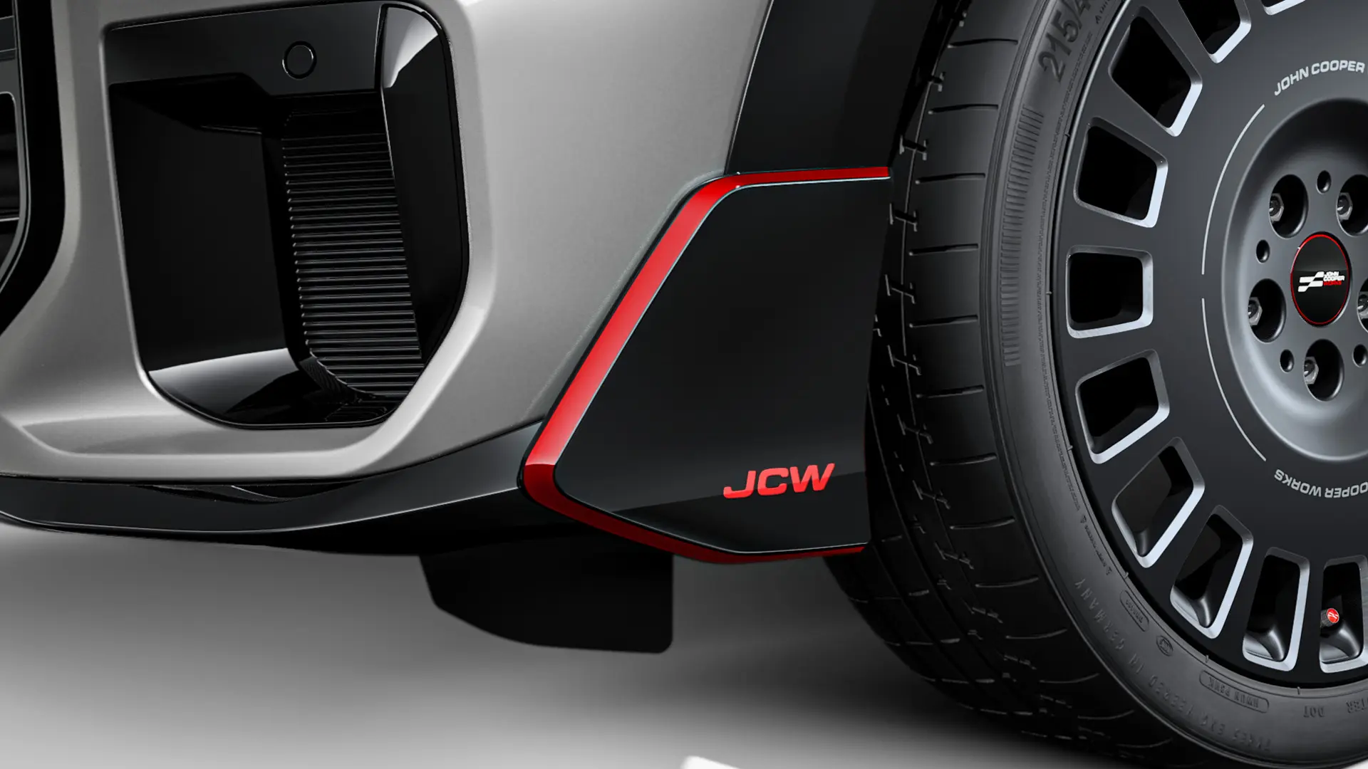 Winglet dianteiro MINI John Cooper Works em preto brilhante com letras JCW vermelhas e tiras decorativas.
