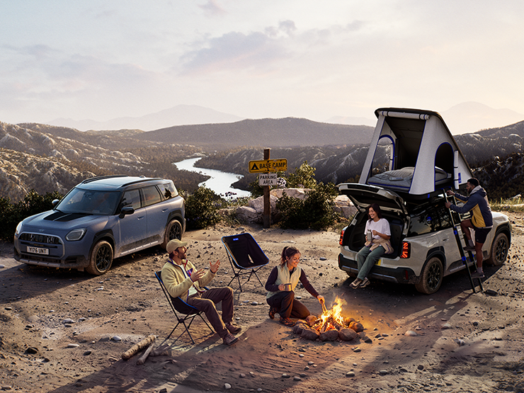 Imagem de dois veículos MINI Countryman Untamed Edition numa montanha ao pôr-do-sol.