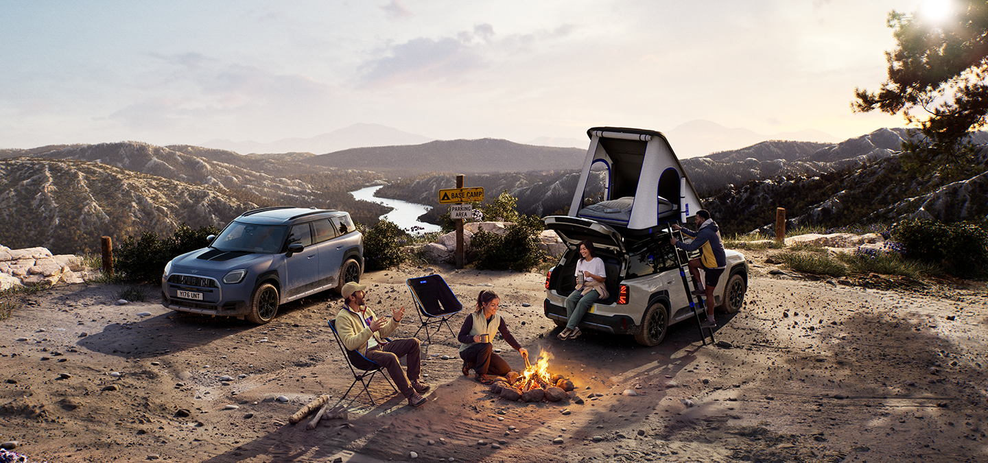 Imagem de dois veículos MINI Countryman Untamed Edition numa montanha ao pôr-do-sol.