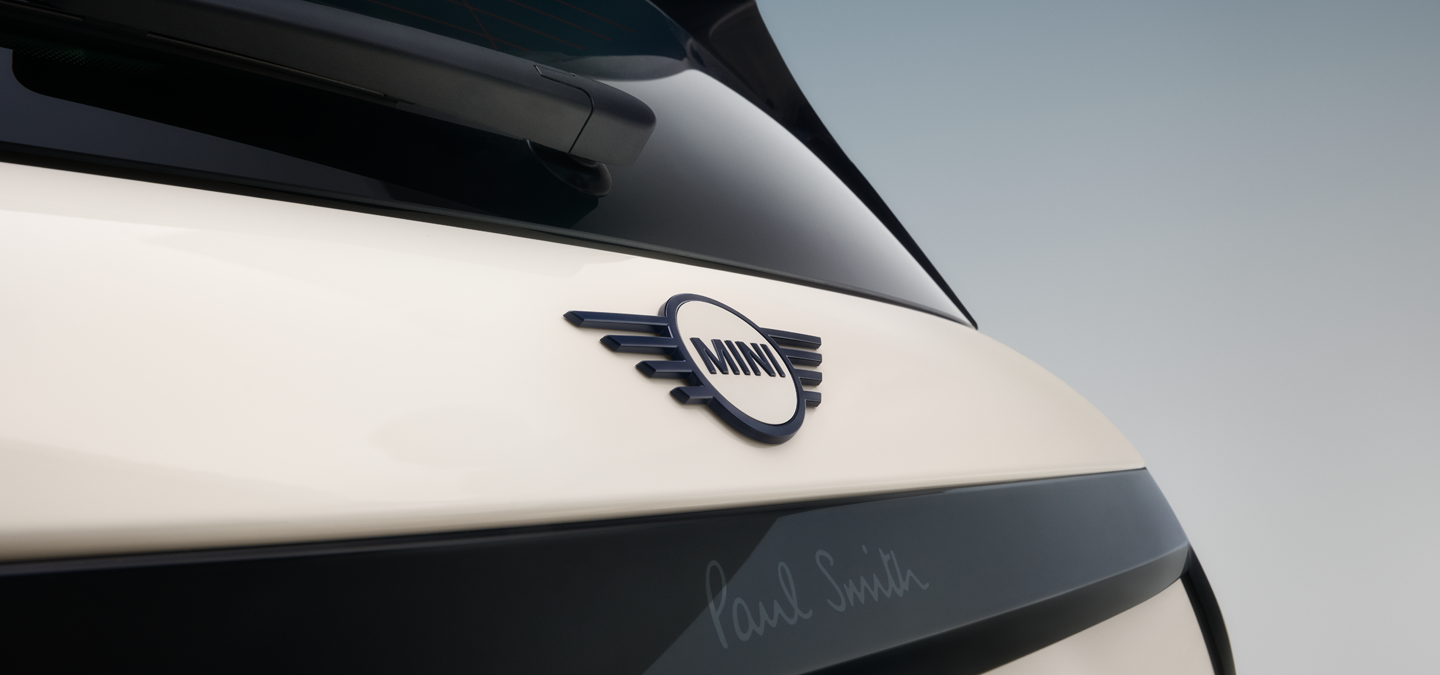 Imagem em grande plano do emblema traseiro em forma de asa do MINI Cooper Paul Smith Edition elétrico, em Inspired White