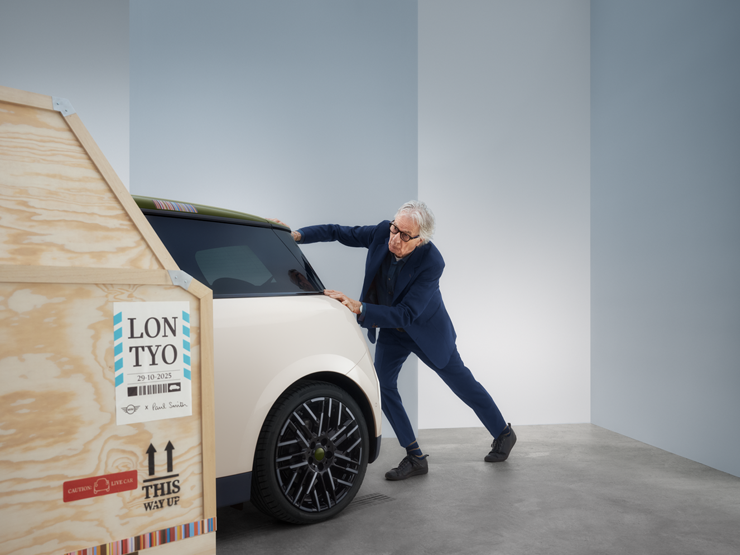 Vista traseira do MINI Cooper Paul Smith Edition elétrico, em Inspired White, com Paul Smith atrás do carro