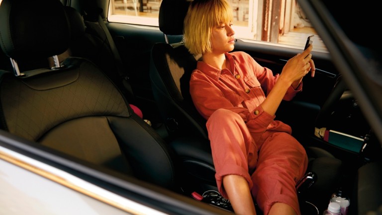 Mulher a fazer marcação de serviço online MINI, no interior do seu MINI Cooper 3 Portas