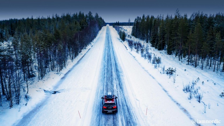 MINI Cooper com suporte de tejadilho numa estrada com neve - perspetiva traseira.