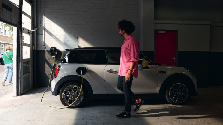 Homem ao lado de um MINI Electric a carregar