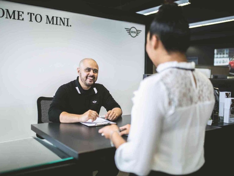 Duas pessoas a conversarem sentados no escritório do MINI.