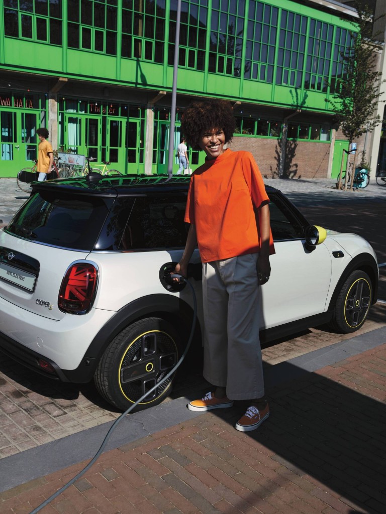 Mulher ao lado do MINI Cooper SE a carregá-lo.