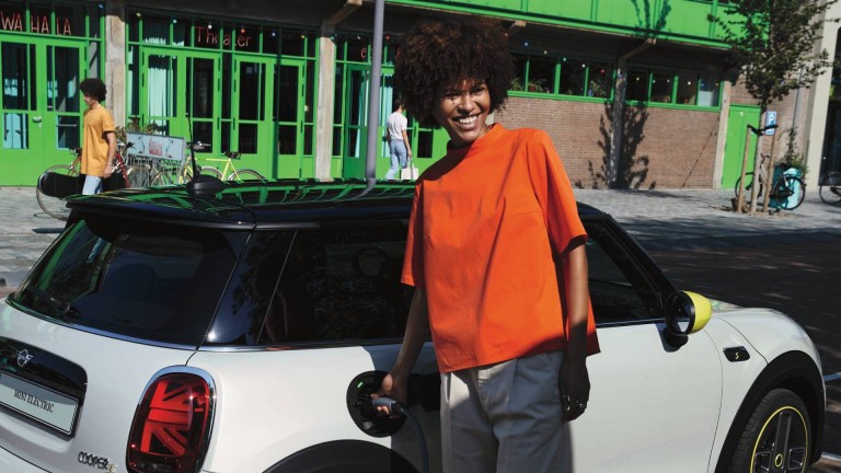 Mulher ao lado do MINI Cooper SE a carregá-lo.