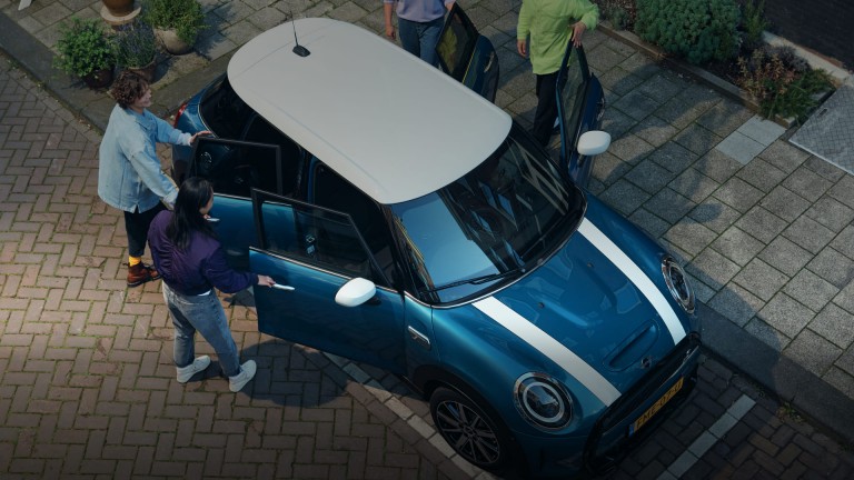 4 pessoas a entrar para o MINI Cooper 5 Portas de cor azul e tejadilho branco.