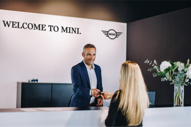 Balcão de receção de parceiro MINI com funcionário e cliente
