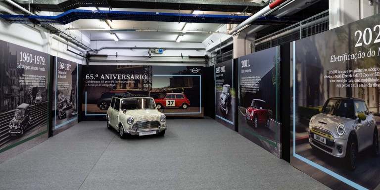 Um MINI Clássico e um MINI Cooper E lado a lado debaixo de árvores.