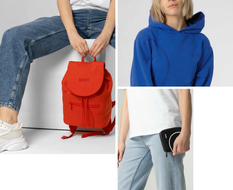 Três peças da nova coleção MINI Lifestyle: uma mochila vermelha, um hoodie com capuz azul e uma carteira preta.