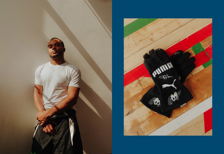 Nicolas Hamilton olha para a câmera. Ele está vestido com uma t-shit branca e um fato de corrida preto, meio puxado para baixo. Imagem das Luvas de corrida: Imagem das luvas pretas personalizadas de Nicolas Hamilton. Elas são pretas e estão personalizadas com sua assinatura.